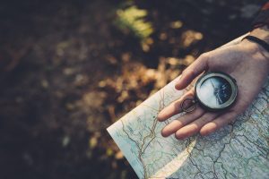 Teenager girl with Compass Reading a Map in the forest