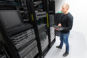 man standing with lap top assessing servers