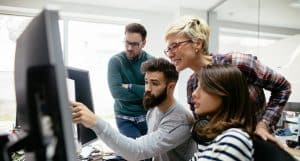 group of people looking over a computer screen at work